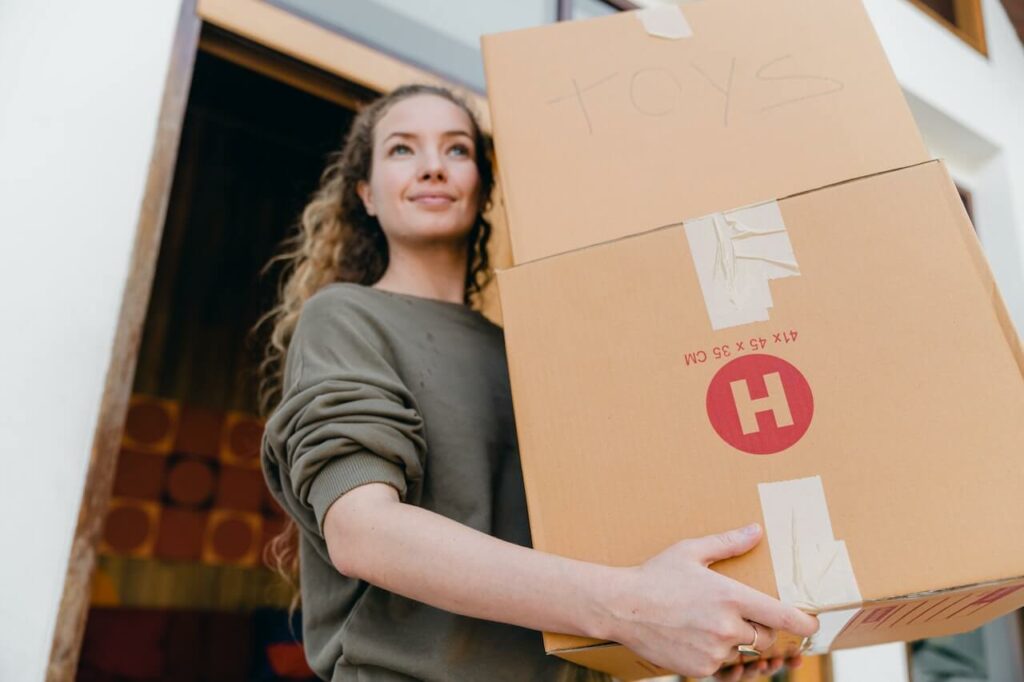Woman in her 20s carrying moving boxes