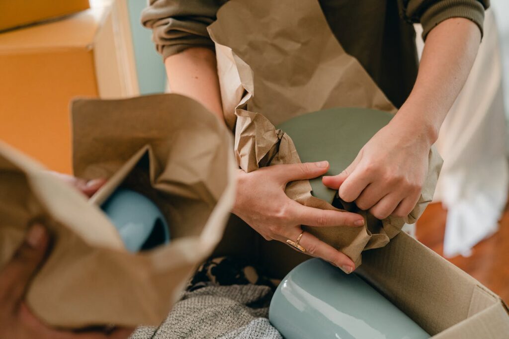 Packing up breakable pottery into boxes with kraft paper